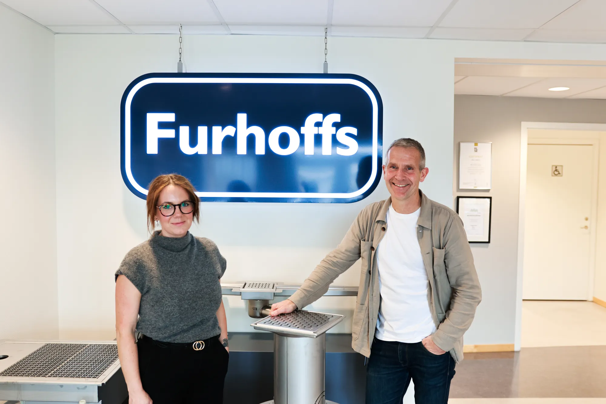 Matilda Magnisson och Peter Larsson på Furhoffs framför entréskylten. 